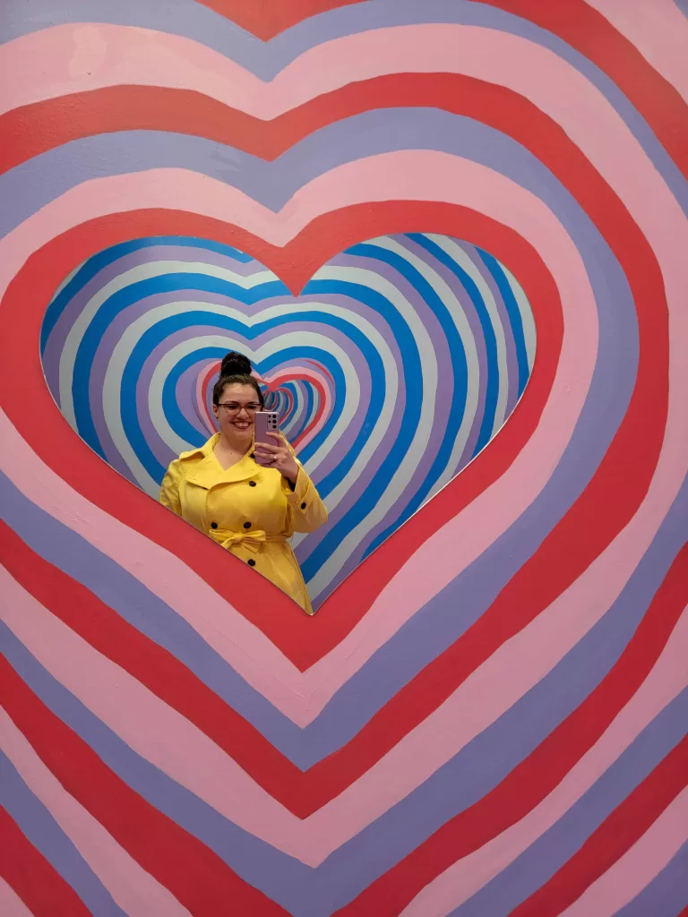 My selfie with a colorful hearts background, to set the stage for the list of Valentine's Day gifts for travelers