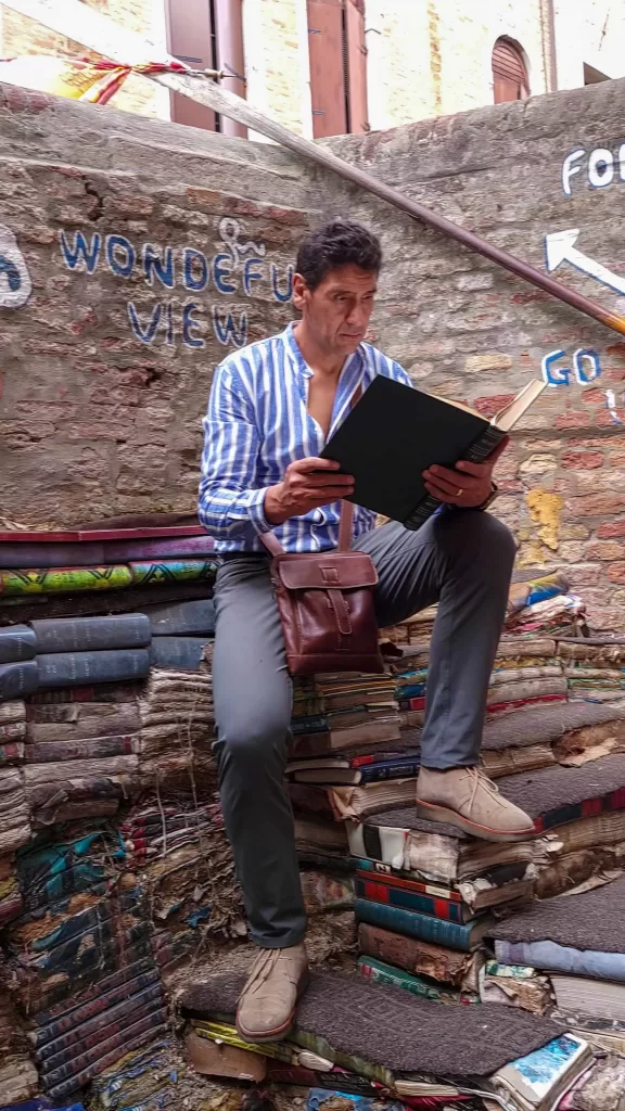 man reading a book at libreria acqua alta in venice