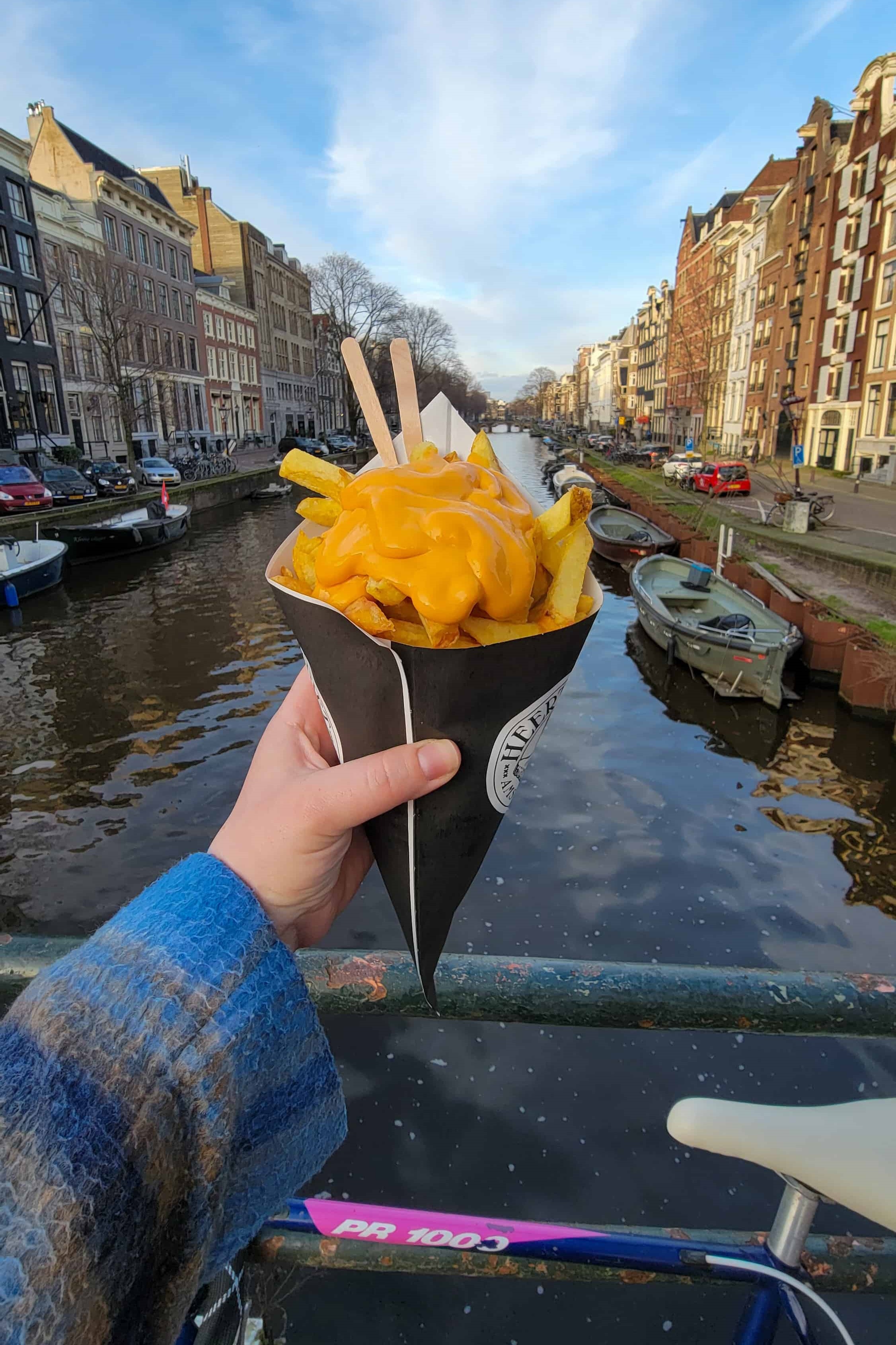 me holding fries in front of a canal in amsterdam