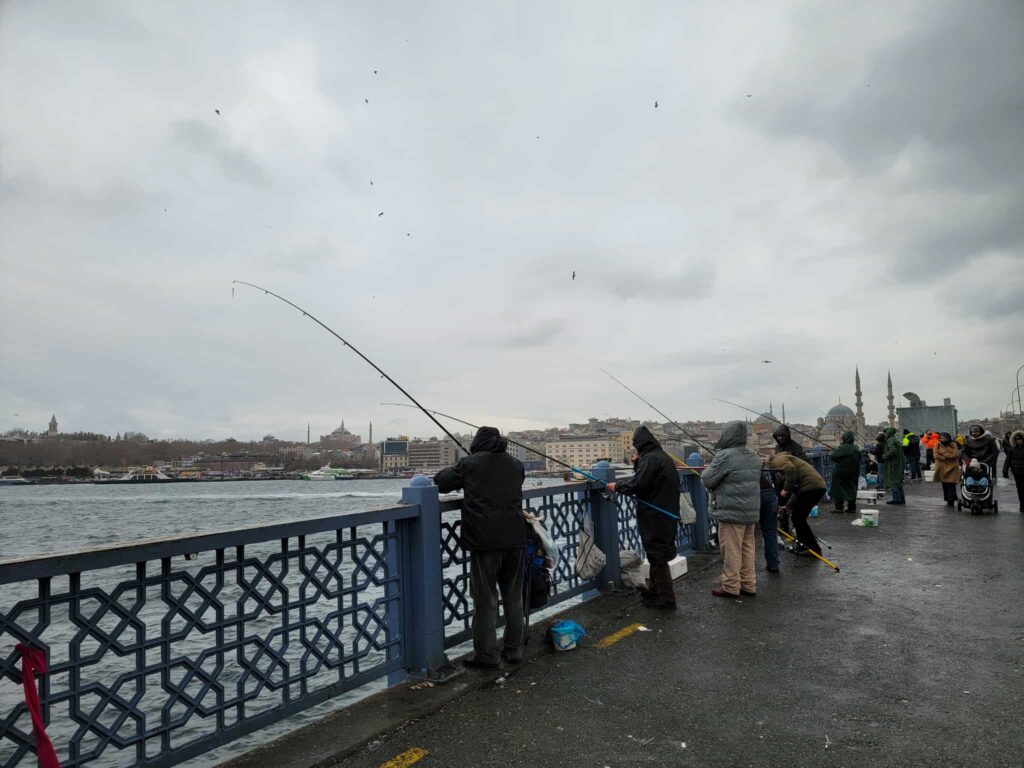 turksih people fishing on the galata bridge in istanbul