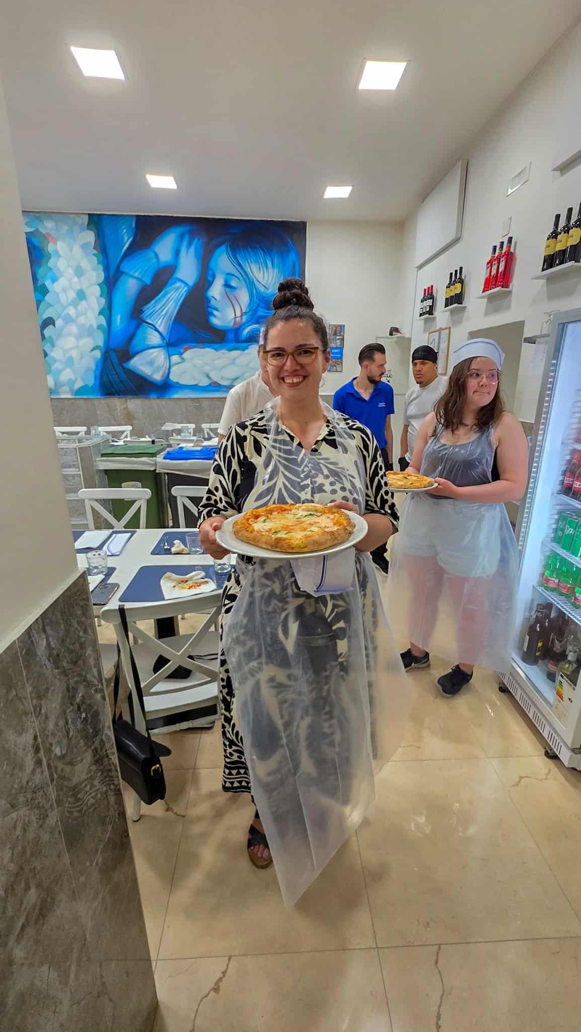 the author holding the pizza she made at a pizza making workshop