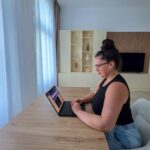 the author at her desk looking at her laptop, writing how to make money while traveling article