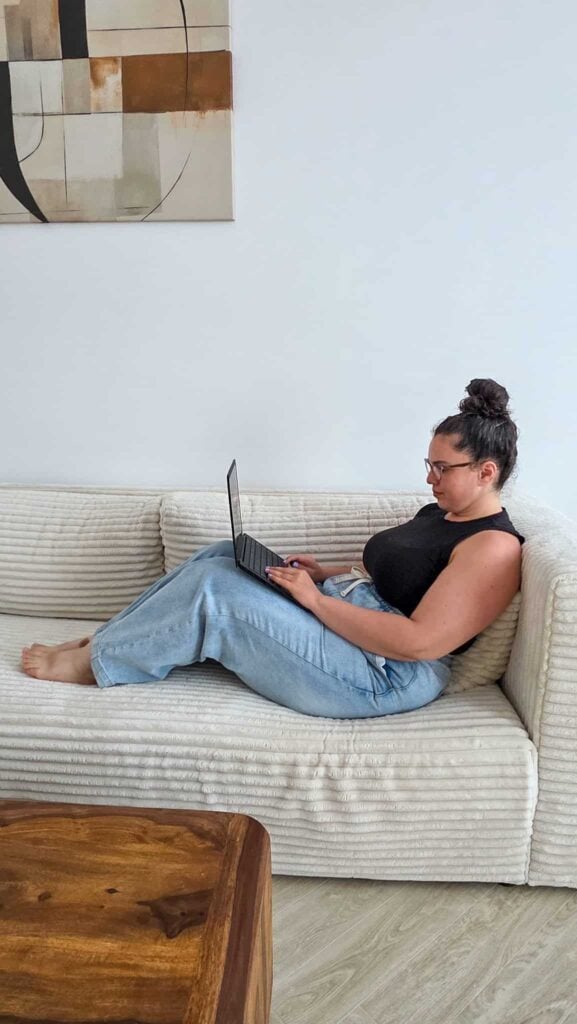 the author on a couch working on the "are blogging courses worth it" blog post