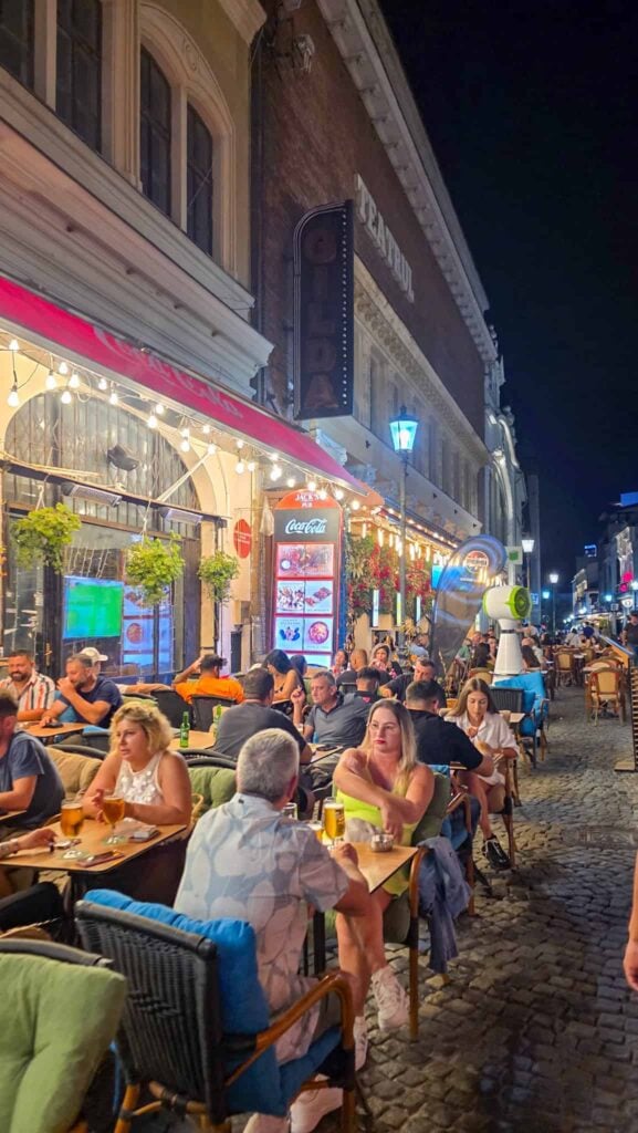 people sitting at tables outside at restaurants in the bucharest old town
