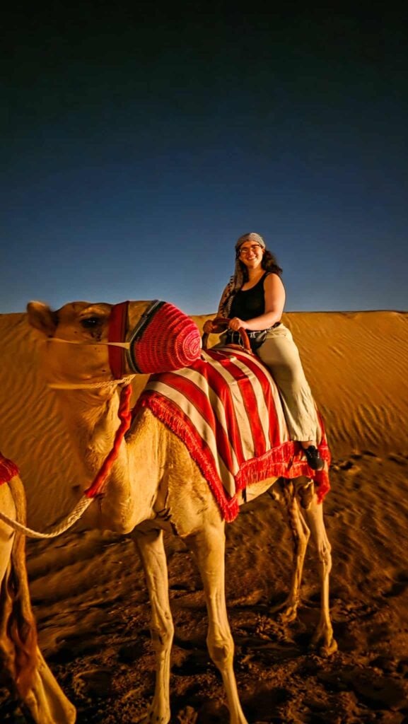 the author riding a camel in the dubai desert